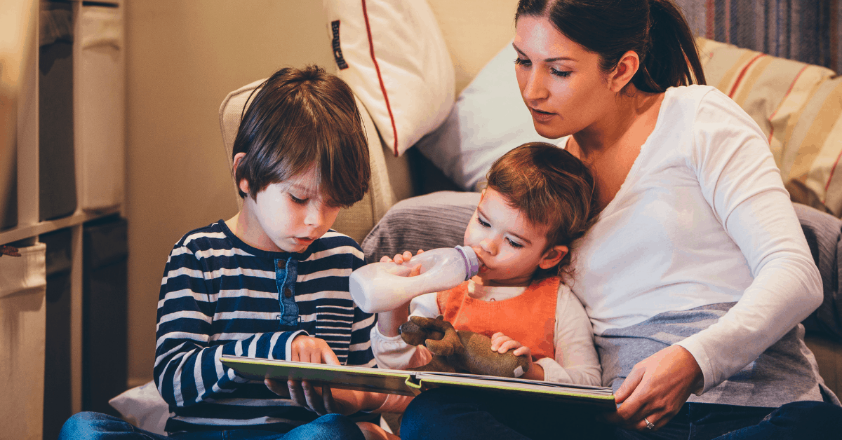A parent reading a children's book with her two young kids