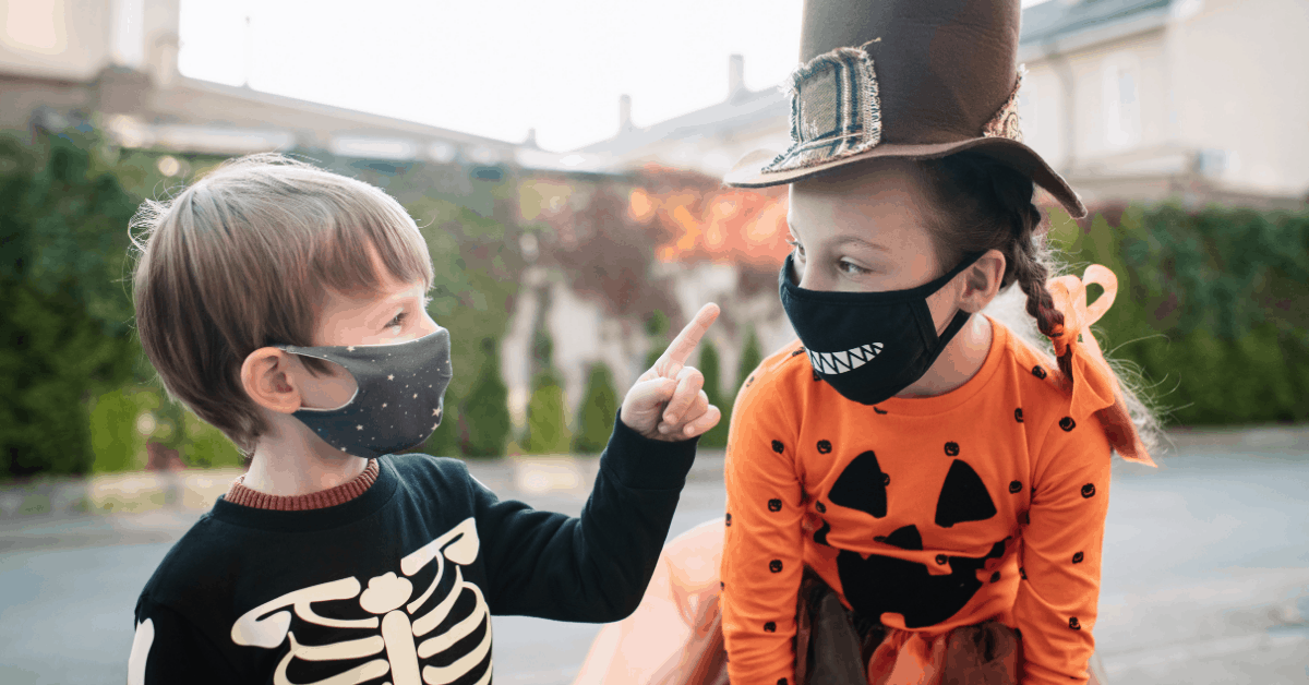 Two children in Halloween costumes wearing COVID masks.