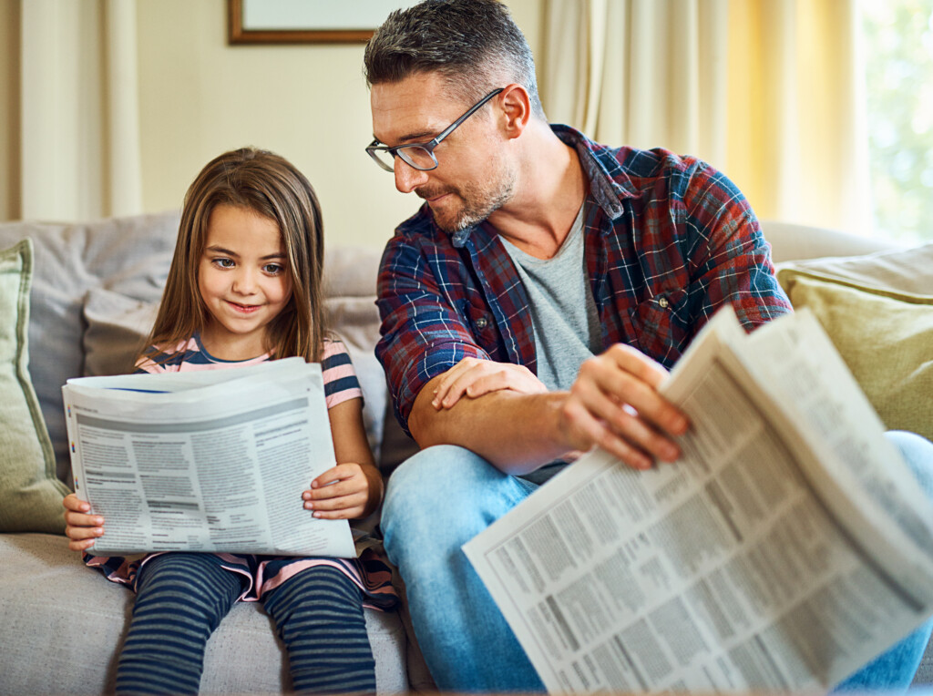 man reading newspaper with child