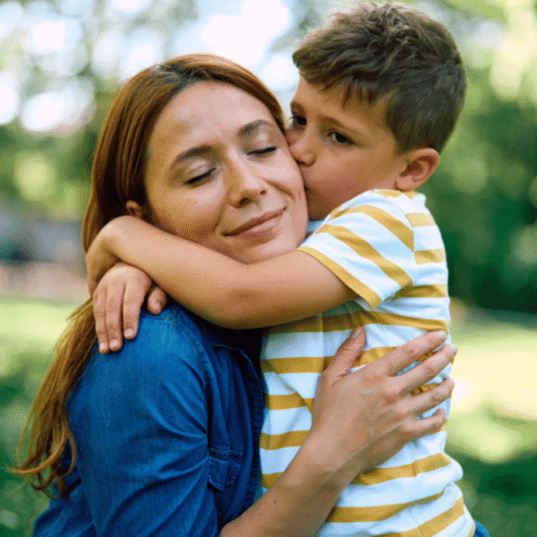 mother hugging young boy child kissing on cheek
